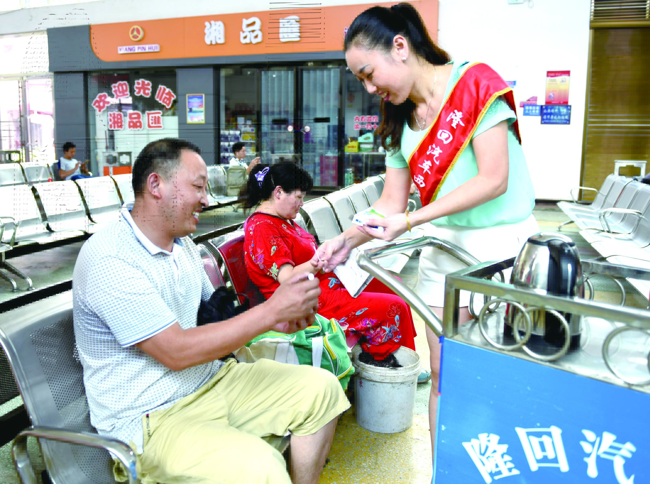 隆回分公司汽車西站工作人員正在為旅客免費(fèi)贈(zèng)送藿香正氣水。